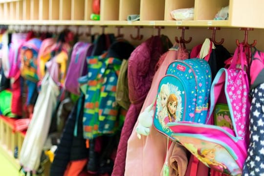 Kinderjacken und Rucksäcke hängen in einer Kindertagesstätte.