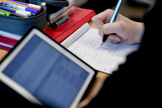 Komplett ausgestattet: Ein Schüler mit Tablet, Stift und Papier im Matheunterricht.