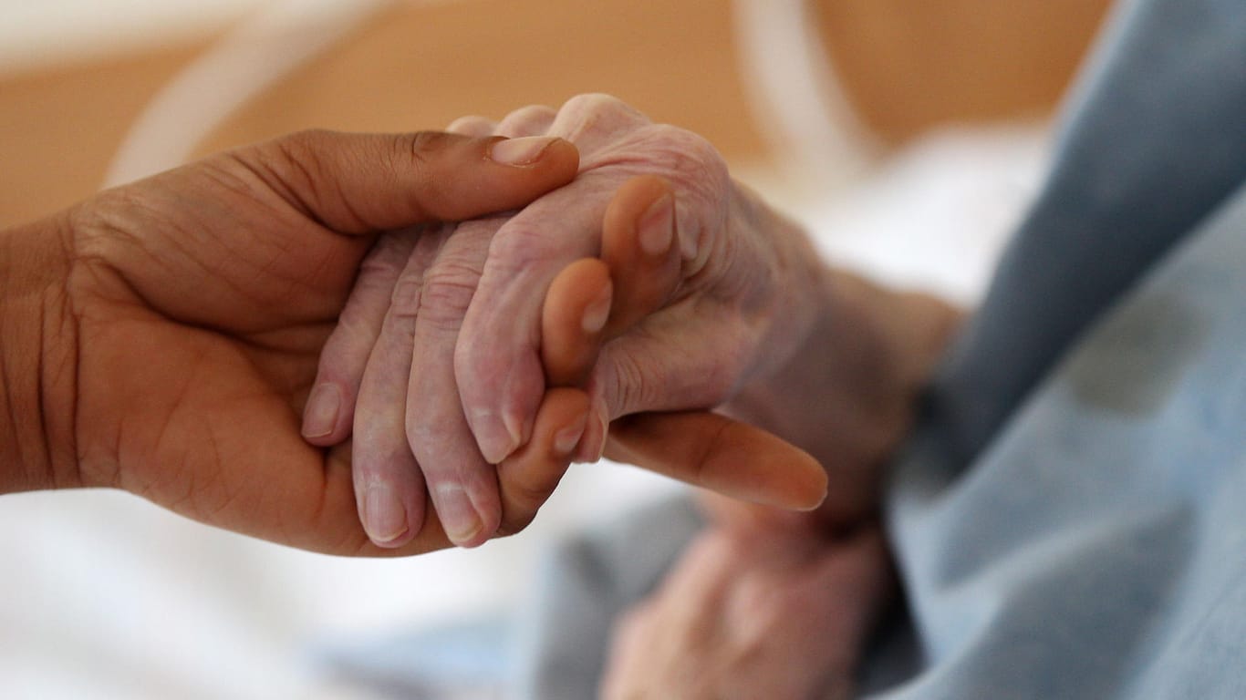 Eine Pflegerin hält die Hand einer Frau (Symbolbild): Eine Pflegerin soll mit Komplizen eine 95-Jährige geprellt haben.