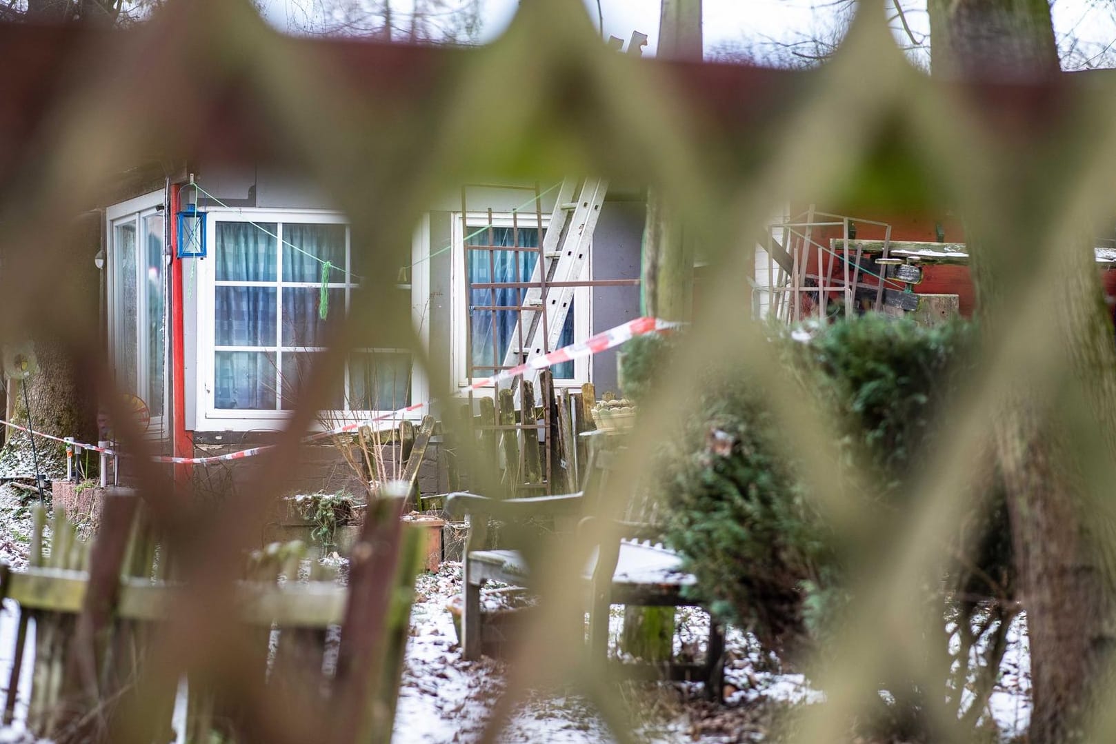 Blick durch einen Zaun auf ein Gebäude auf dem Campingplatz Eichwald, das mit einem Polizeiabsperrband versehen ist.