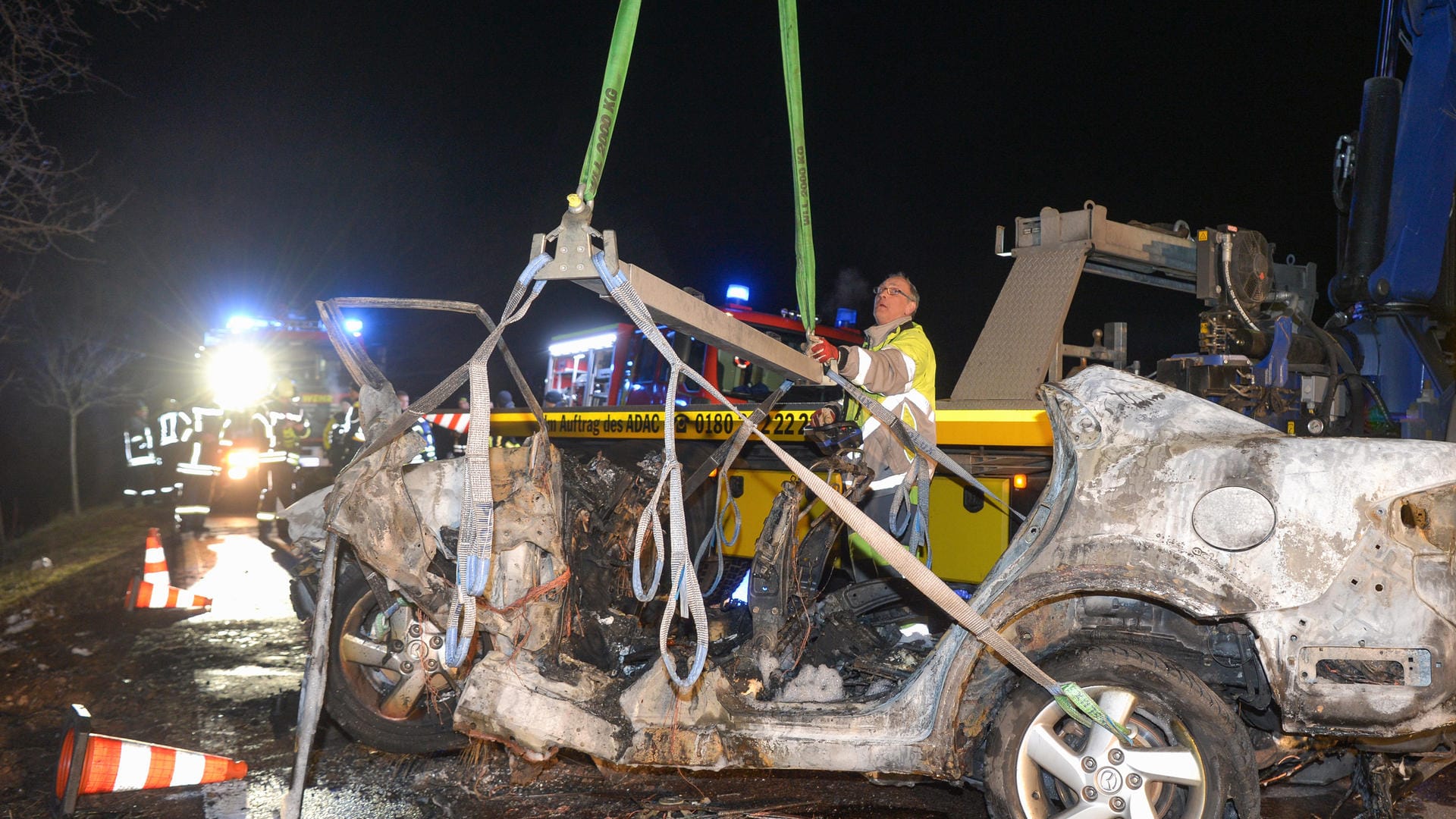 Auf einer Landstraße wird ein ausgebranntes Auto von einem Abschleppunternehmen aufgeladen: Bei dem Autounfall nahe Köthen sind drei Menschen, darunter ein Kind, verbrannt.