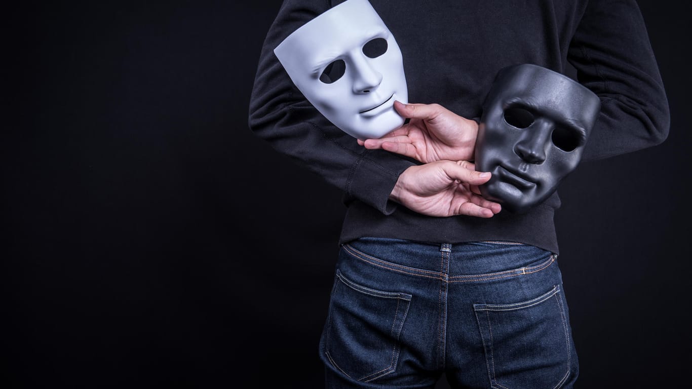 Ein Mann hält zwei Masken hinter dem Rücken: Identitätsdiebstahl im Internet passiert häufiger, als viele denken.