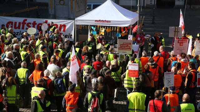 Demonstranten in bunten Westen stehen vor dem Düsseldorfer Rathaus.