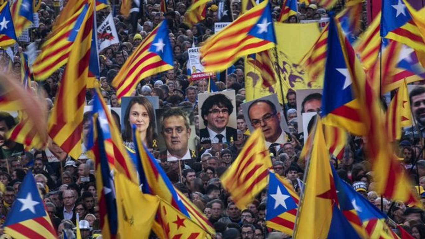 Demonstranten tragen bei der Massenkundgebung in Barcelona Fahnen und Bilder ehemaliger katalanischer Regierungmitglieder.