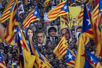 Demonstranten tragen bei der Massenkundgebung in Barcelona Fahnen und Bilder ehemaliger katalanischer Regierungmitglieder.