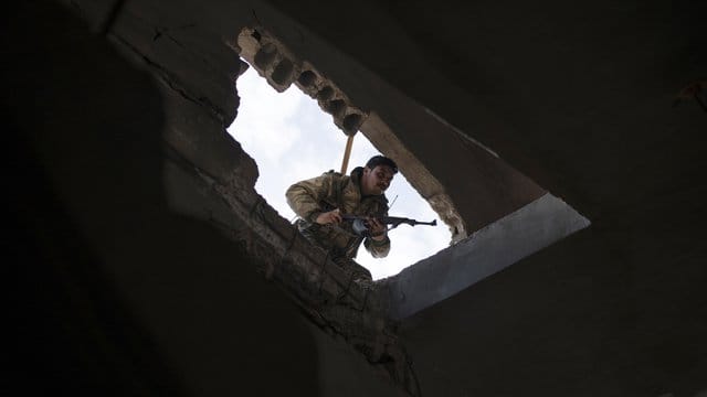 Ein Kämpfer der von den USA unterstützten Syrischen Demokratischen Kräfte durchsucht ein Gebäude in Baghus. Ein Kämpfer der von den USA unterstützten Syrischen Demokratischen Kräfte durchsucht ein Gebäude in Baghus.