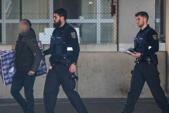 Polizisten begleiten einen Mann (l) in ein Terminal des Flughafens, von wo aus er mit einer gecharterten Maschine am Abend nach Afghanistan abgeschoben werden soll.