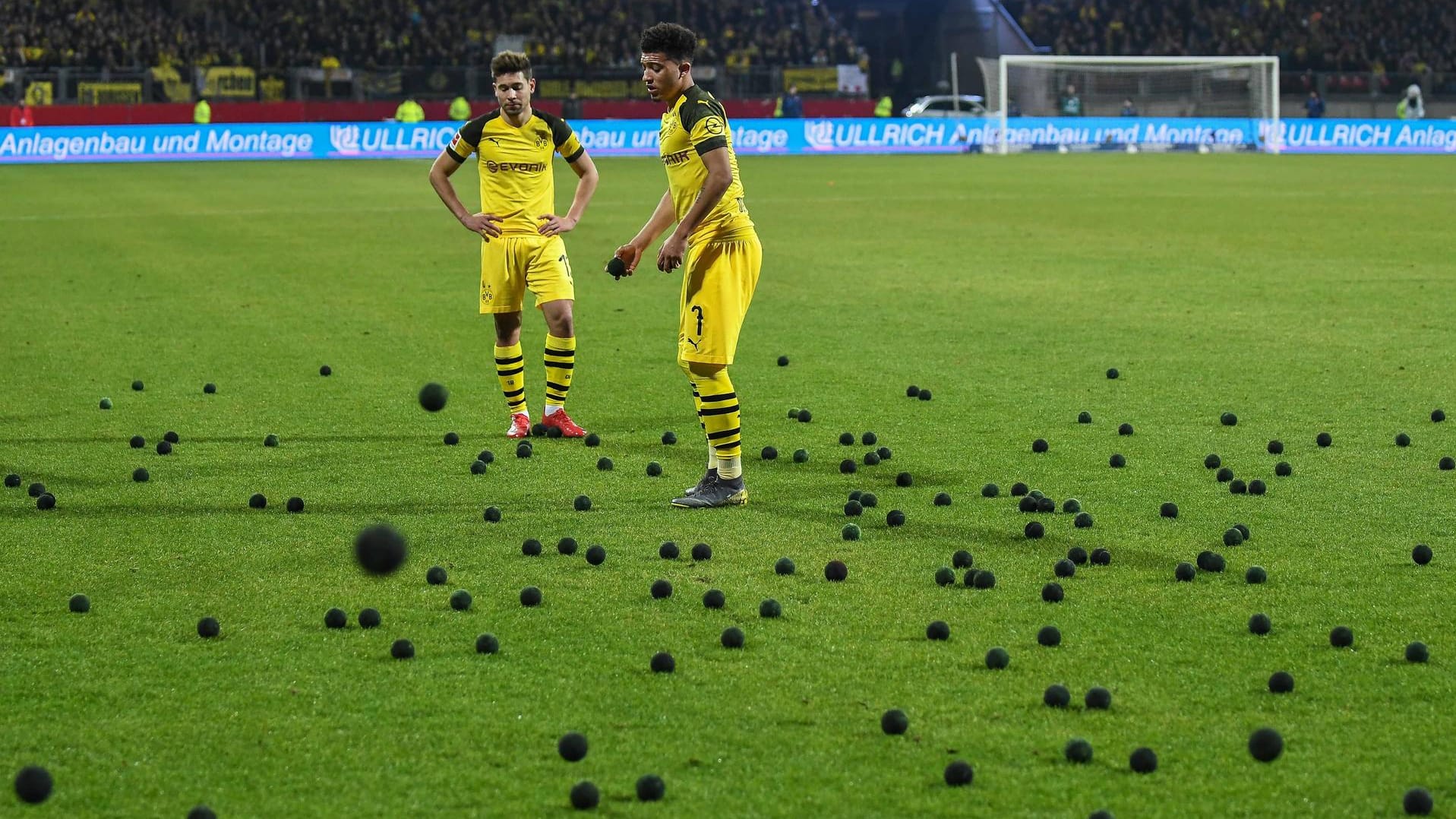 Als BVB-Akteur Jadon Sancho (r.) einen Eckstoß ausführen will, fliegen aus der Nürnberger Fankurve schwarze Tennisbälle auf den Platz.