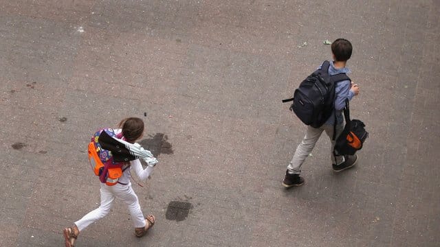 Zwei Schüler gehen über den Hof einer Schule.