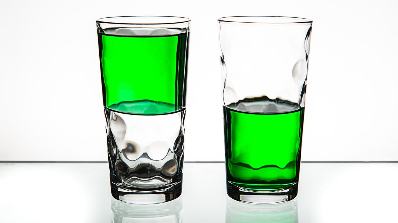 Two glasses, both half-full of green liquid.
