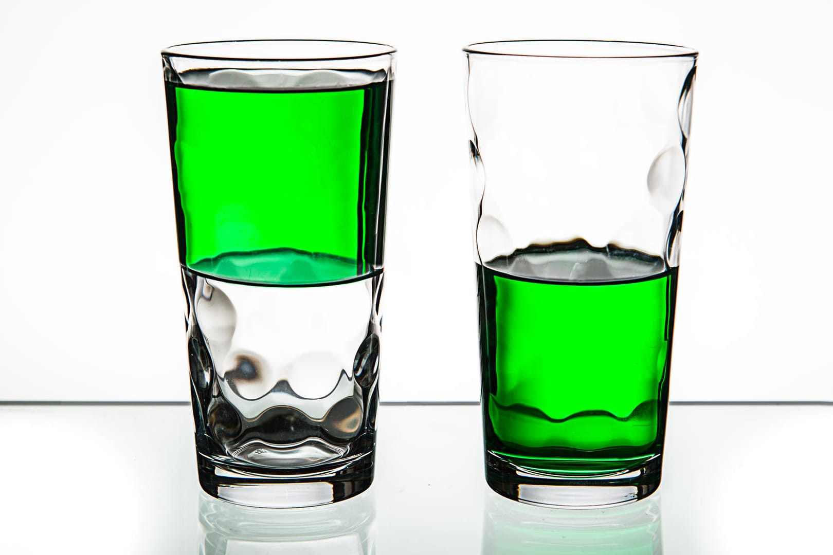 Two glasses, both half-full of green liquid.