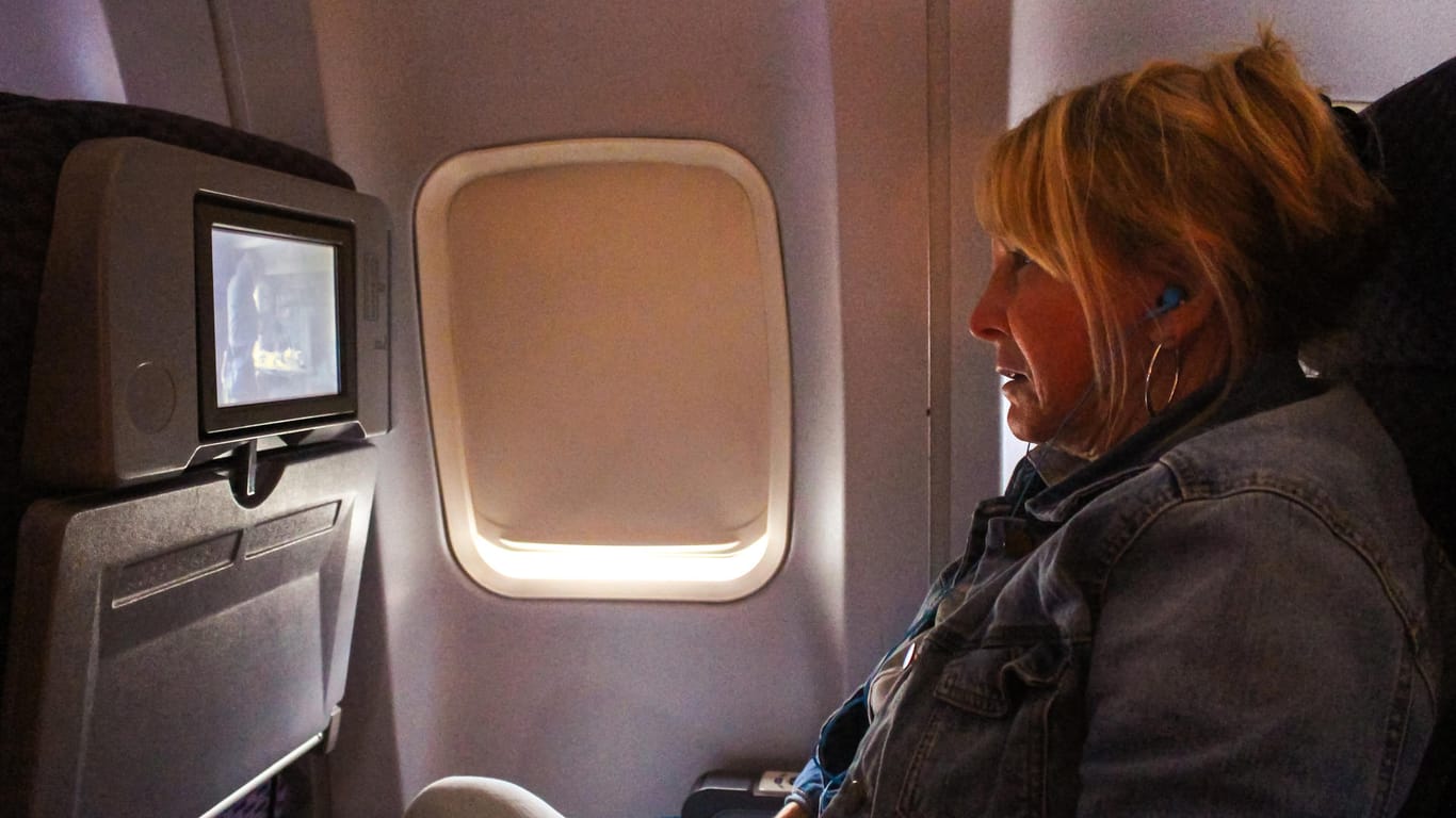 Eine Frau schaut im Flugzeug einen Film: Singapore Airlines hat in seine Entertainment Systeme Kameras eingebaut.
