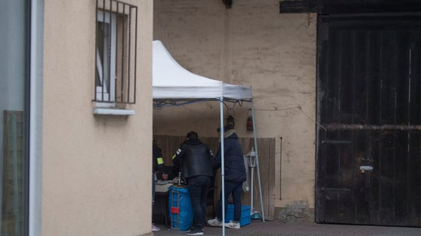 Beamte der Kriminalpolizei sichern im Hinterhof eines Hauses sichergestellte Asservate.