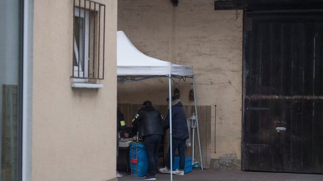 Beamte der Kriminalpolizei sichern im Hinterhof eines Hauses sichergestellte Asservate.