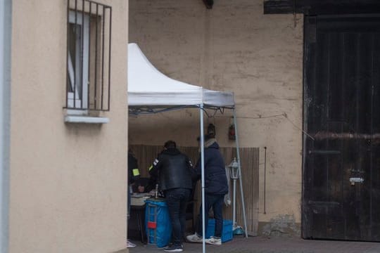 Beamte der Kriminalpolizei sichern im Hinterhof eines Hauses sichergestellte Asservate.