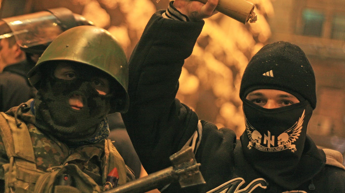16. Februar 2014: Unter den Demonstranten waren auch einige Rechtsextreme und Fußball-Hooligans. Der rechte Mann hält eine selbstgebasteltete Rauchbombe hoch.