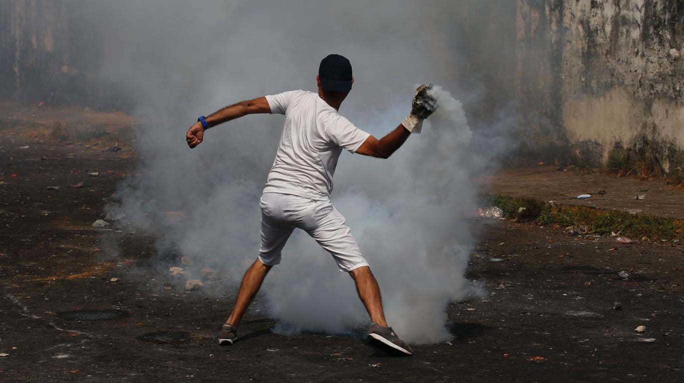 Demonstrant in Urena, Venezuela, wirft eine Tränengasgranate zurück auf die Einsatzkräfte: An der Grenze zu Kolumbien spitzte sich die Lage am Samstag zu.