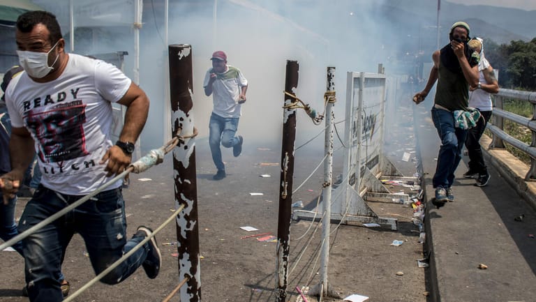 Kolumbien, Cucuta: Demonstranten auf der Brücke über den Grenzfluss fliehen vor dem Tränengas der venezolanischen Nationalgarde.