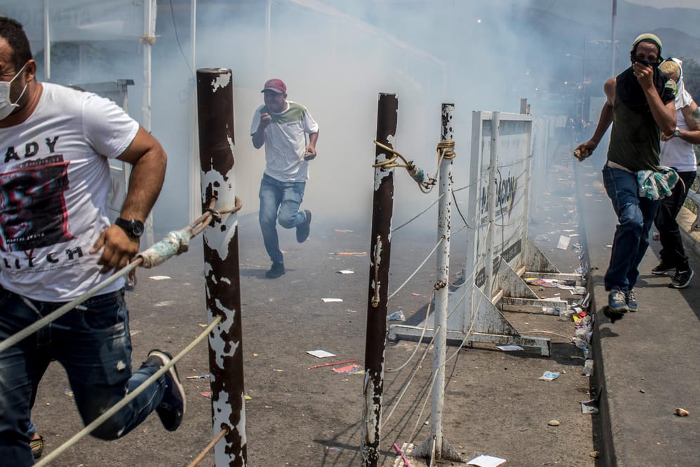 Kolumbien, Cucuta: Demonstranten auf der Brücke über den Grenzfluss fliehen vor dem Tränengas der venezolanischen Nationalgarde.
