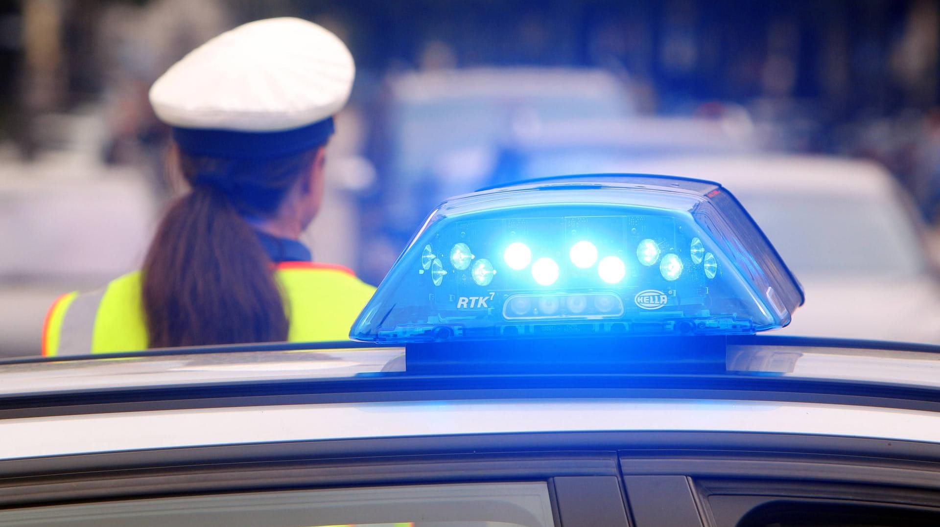 Einsatzwagen der Polizei mit eingeschaltetem Blaulicht und Polizistin mit Haarzopf: Nachbarn hatten die Polizei alarmiert, weil sie im Keller Drogen gesehen hatten.