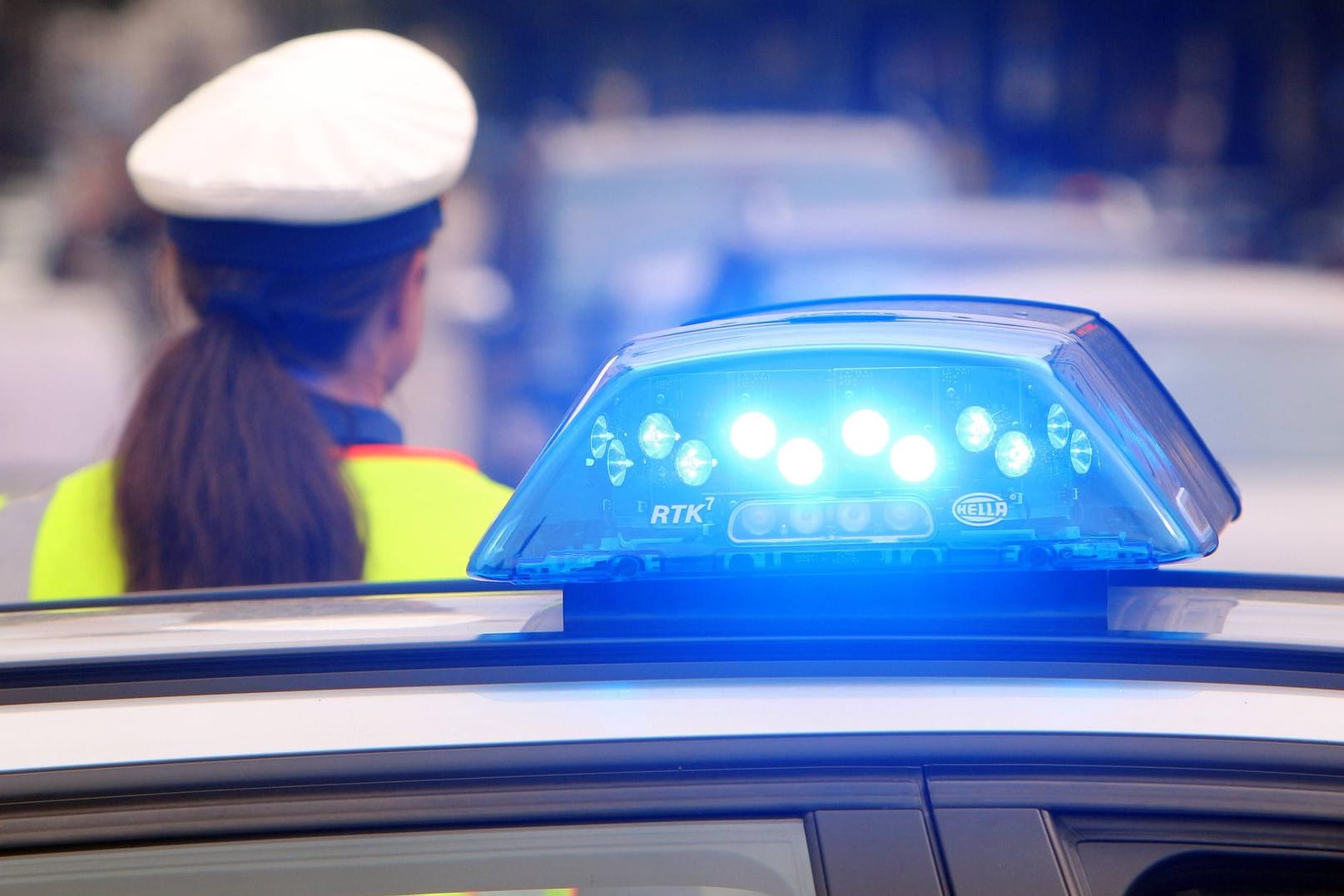 Einsatzwagen der Polizei mit eingeschaltetem Blaulicht und Polizistin mit Haarzopf: Nachbarn hatten die Polizei alarmiert, weil sie im Keller Drogen gesehen hatten.