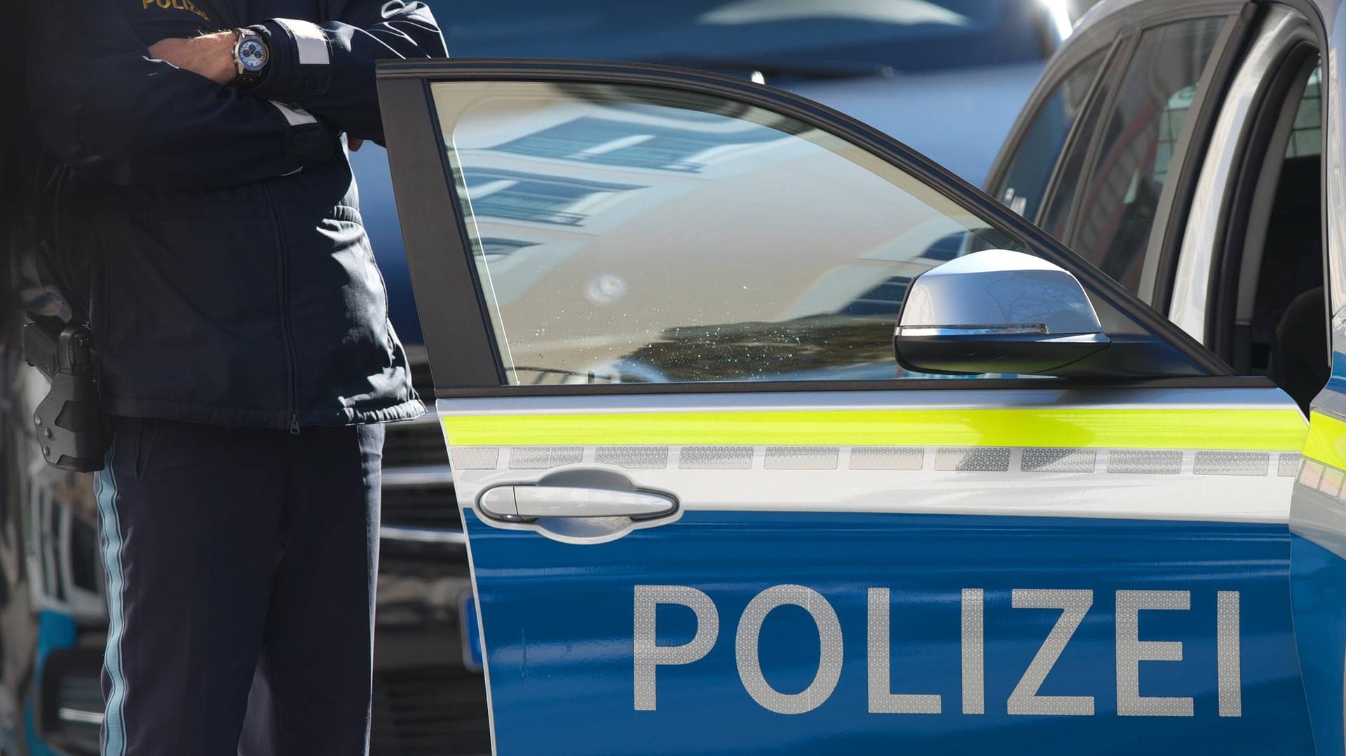 Polizist steht am Polizeiauto: Die Polizei hat das Verhalten von Gaffern satt. (Symbolfoto)