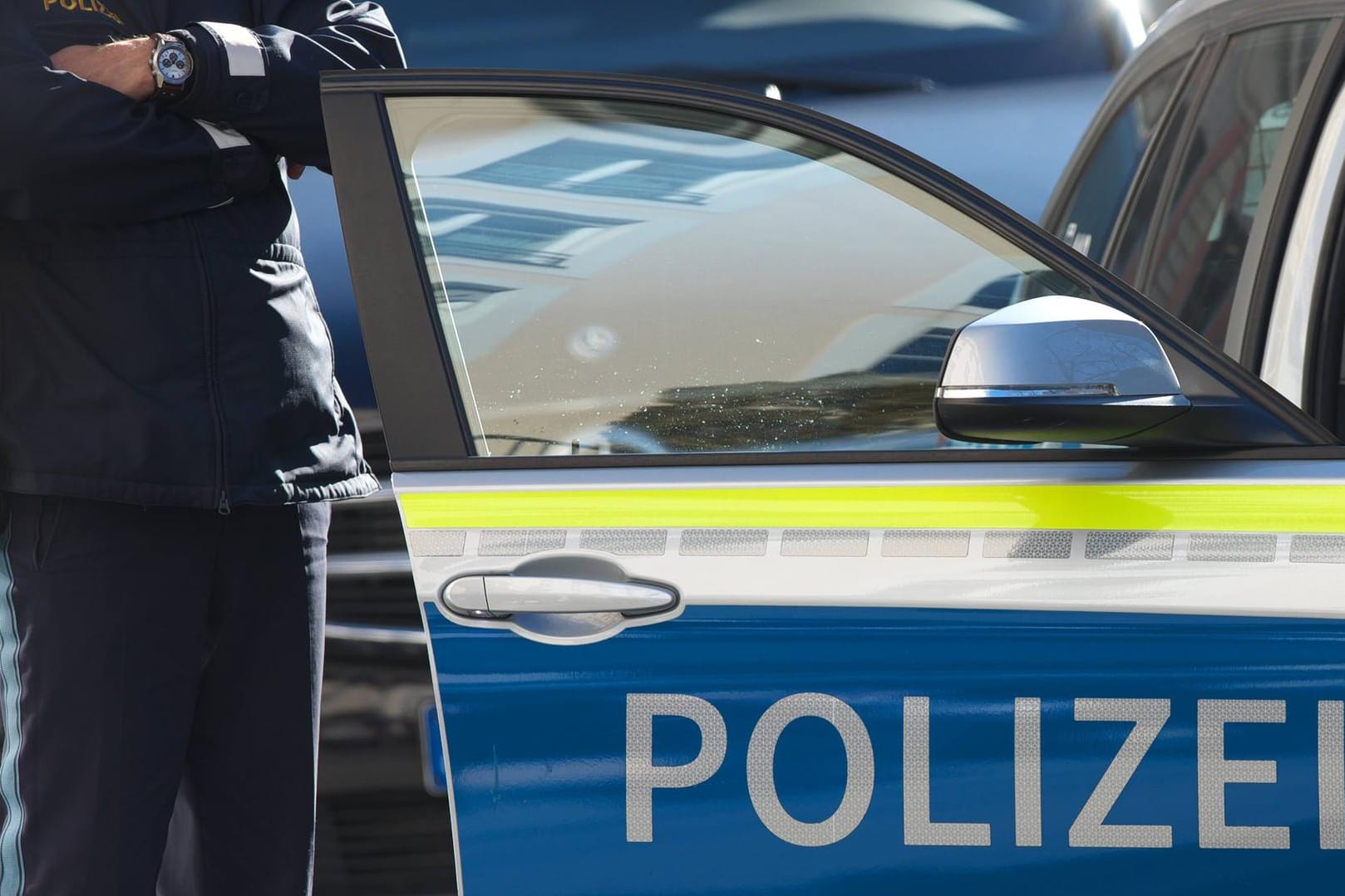 Polizist steht am Polizeiauto: Die Polizei hat das Verhalten von Gaffern satt. (Symbolfoto)