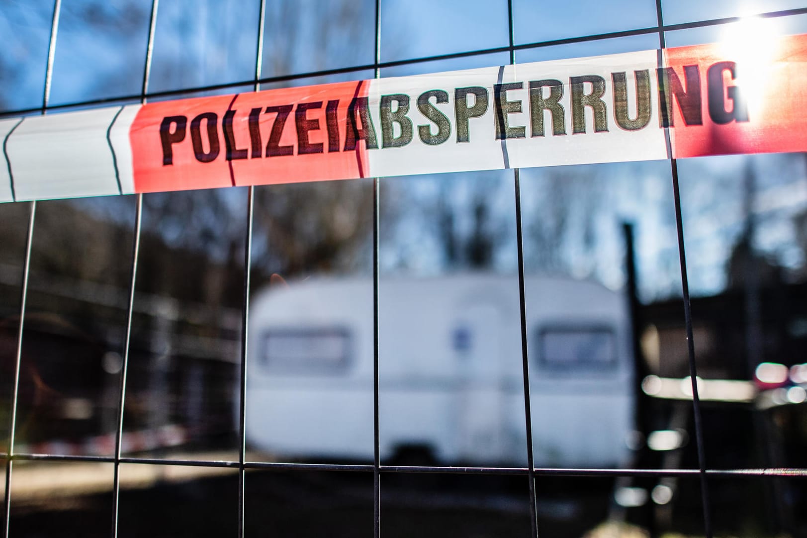 "Noch schlimmer als befürchtet": Ein Zaun mit einer Banderole versperrt den Weg zum Campingwagen eines mutmaßlichen Täters in dem Missbrauchsskandal.