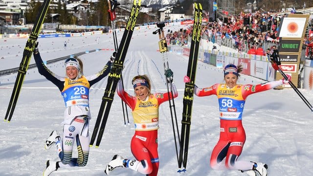 Therese Johaug (M) und Ingvild Flugstad Östberg (r) und Frida Karlsson feiern in Seefeld ihre Langlauf-Medaillen.