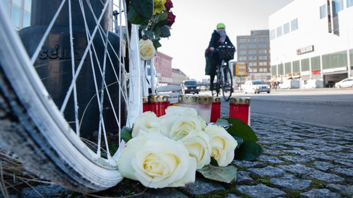Blumen und Kerzen sind vor einem weißen Geisterrad an der Stelle eines tödlichen Radunfalls in Berlin-Mitte aufgestellt.