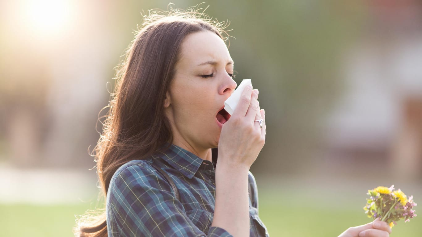 Frau niest: Viele Menschen leiden gerade im Frühling unter Heuschnupfen.