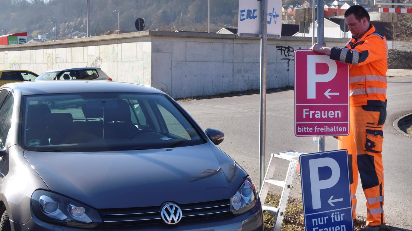 Eichstätt in Bayern: Ein Mitarbeiter der Stadt montiert an einem Parkplatz ein neues, pinkfarbenes Verkehrsschild.