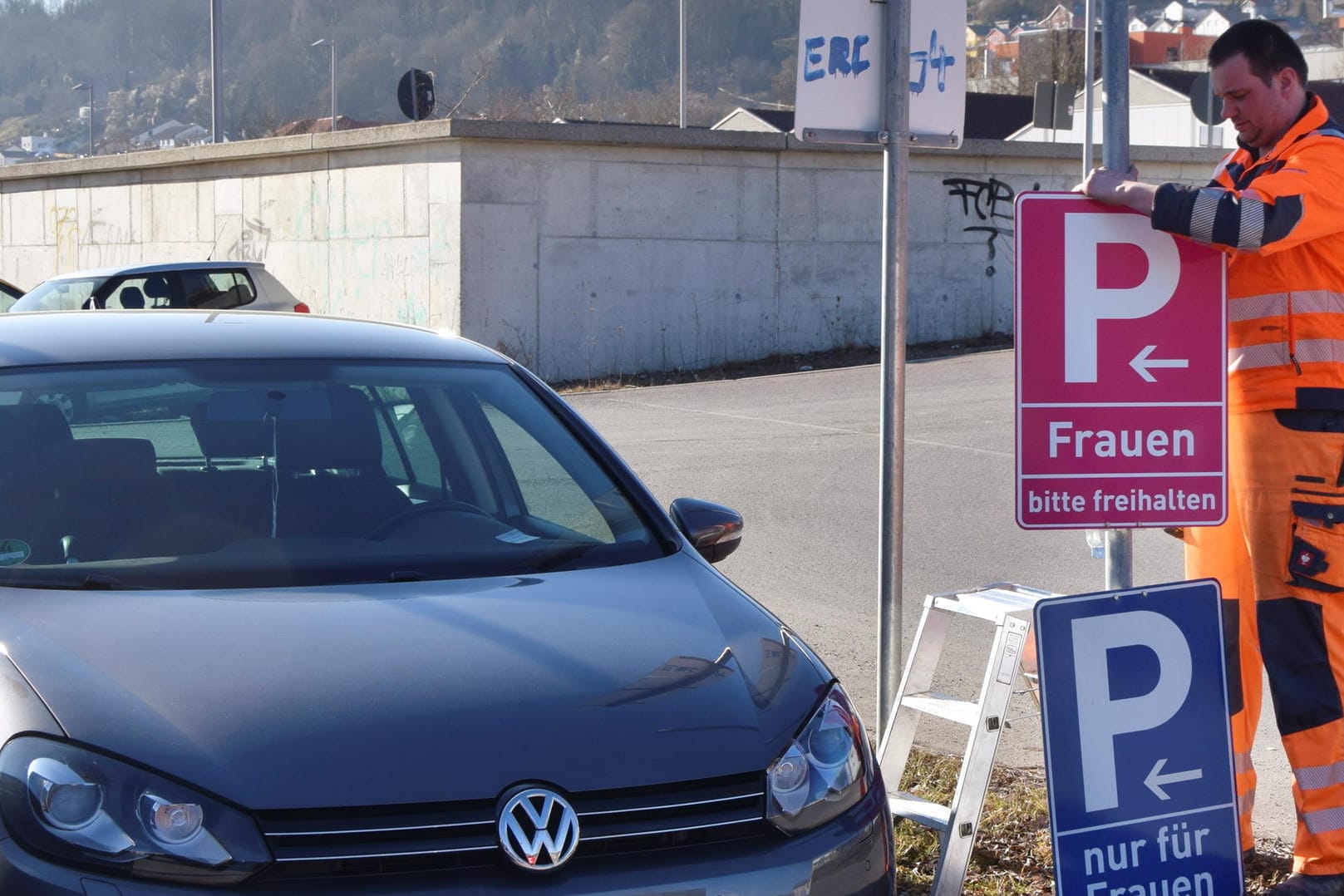Eichstätt in Bayern: Ein Mitarbeiter der Stadt montiert an einem Parkplatz ein neues, pinkfarbenes Verkehrsschild.