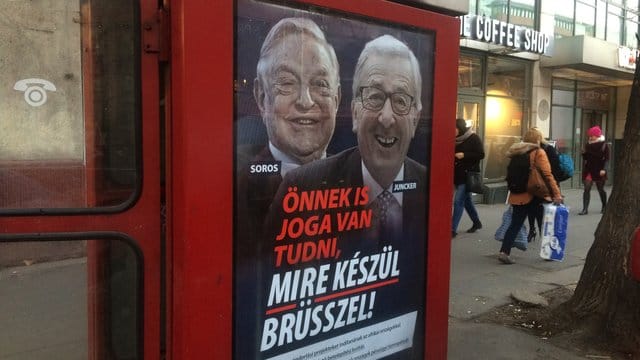Ein Plakat mit dem ungarisch-amerikanischen Milliardär George Soros und dem Präsidenten der EU-Kommission an einer Telefonzelle in Budapest. Ein Plakat mit dem ungarisch-amerikanischen Milliardär George Soros und dem Präsidenten der EU-Kommission an einer Telefonzelle in Budapest.