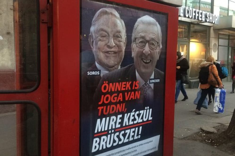 Ein Plakat mit dem ungarisch-amerikanischen Milliardär George Soros und dem Präsidenten der EU-Kommission an einer Telefonzelle in Budapest.
