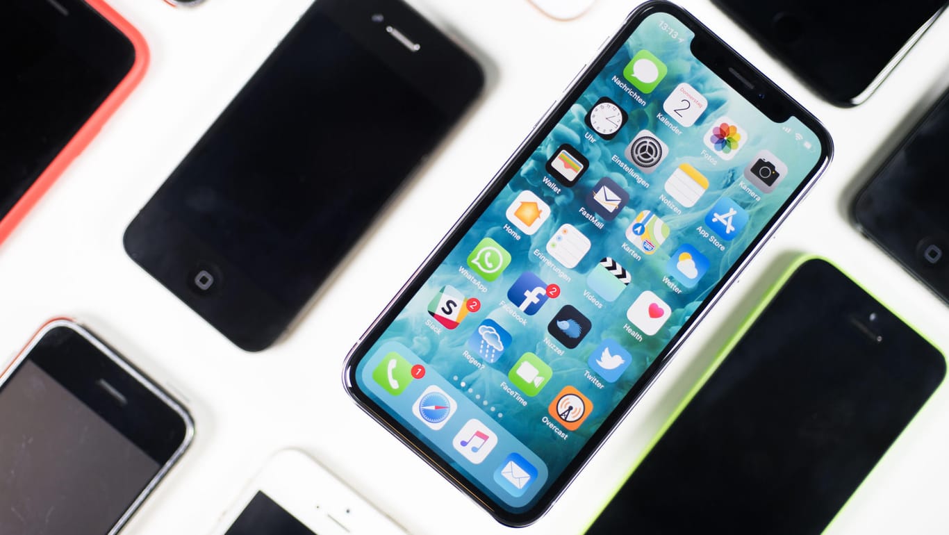 Ein iPhone X liegt neben iPhones anderer Generationen auf einem Tisch. Deren Preise sinken unterschiedlich schnell.