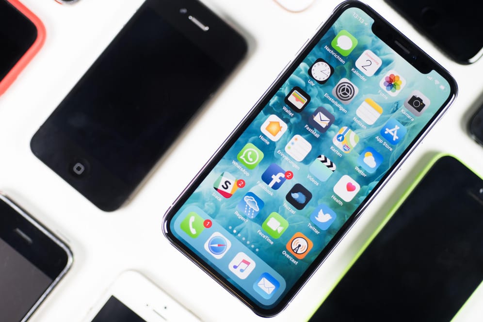 Ein iPhone X liegt neben iPhones anderer Generationen auf einem Tisch. Deren Preise sinken unterschiedlich schnell.