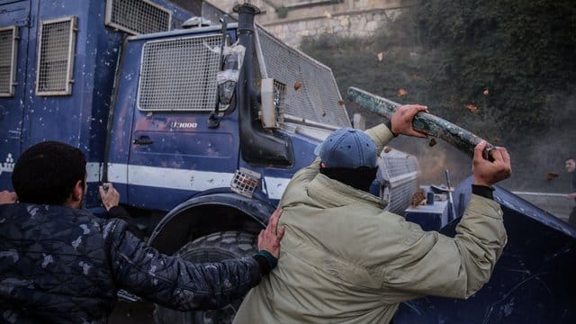 Demonstranten schlagen bei einer Demonstration auf ein gepanzertes Polizeifahrzeug ein. Demonstranten schlagen bei einer Demonstration auf ein gepanzertes Polizeifahrzeug ein.