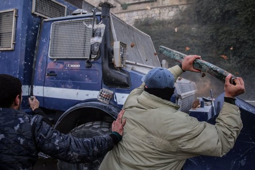 Demonstranten schlagen bei einer Demonstration auf ein gepanzertes Polizeifahrzeug ein.