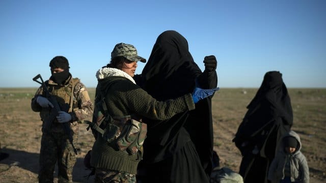 Eine Frau wird von einer Soldatin in einem Kontrollbereich der SDF durchsucht, nachdem sie aus dem verbliebenen Gebiet des IS evakuiert wurde. Eine Frau wird von einer Soldatin in einem Kontrollbereich der SDF durchsucht, nachdem sie aus dem verbliebenen Gebiet des IS evakuiert wurde.