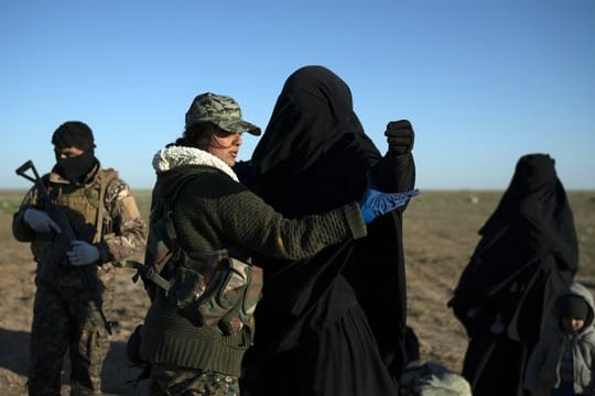 Eine Frau wird von einer Soldatin in einem Kontrollbereich der SDF durchsucht, nachdem sie aus dem verbliebenen Gebiet des IS evakuiert wurde.