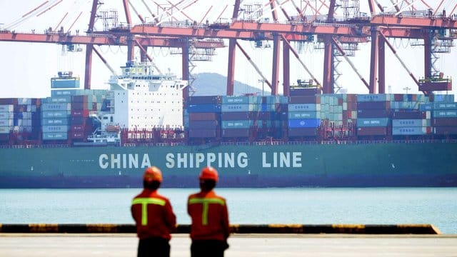 Hafenarbeiter beobachten im Hafen von Qingdao die Beladung eines Containerschiffs. Hafenarbeiter beobachten im Hafen von Qingdao die Beladung eines Containerschiffs.