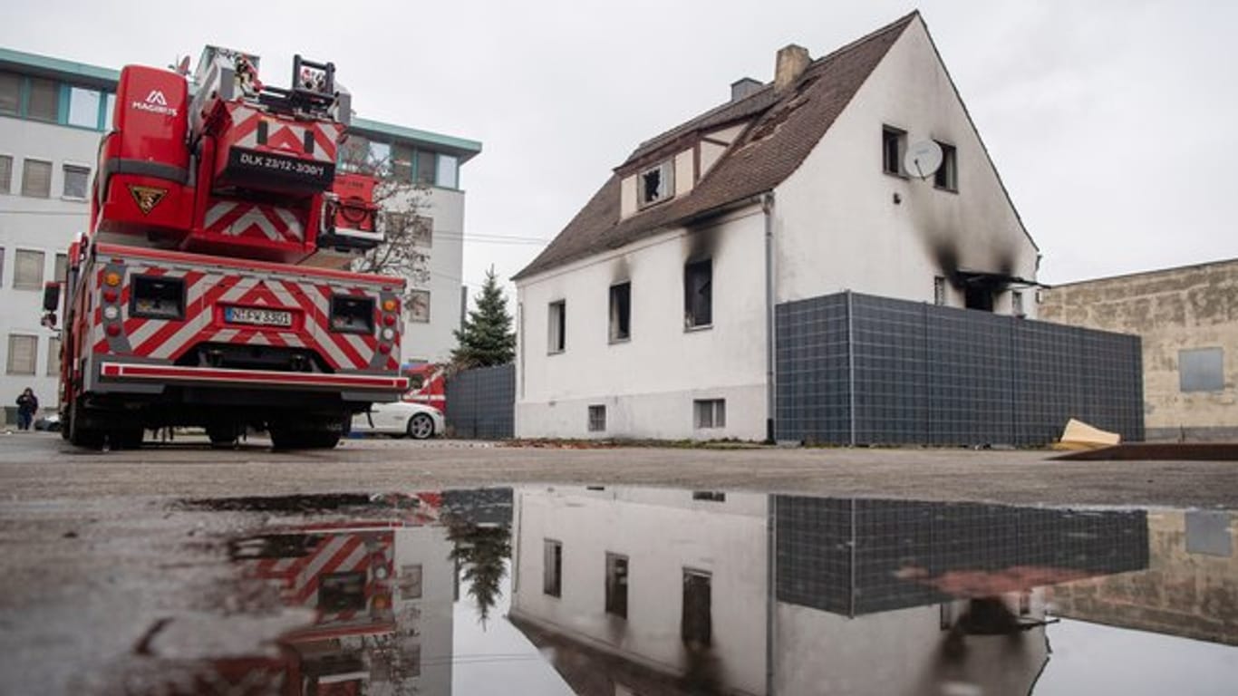 Ein Leiterwagen der Feuerwehr steht neben einem Haus mit Brandspuren: In den Flammen sind fünf Menschen ums Leben gekommen.