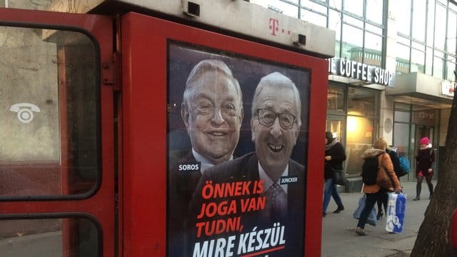 An einer Telefonzelle in Budapest hängt ein Plakat mit den Konterfeis von George Soros und Jean-Claude Juncker mit der Unterschrift "Sie haben ein Recht darauf zu wissen, was Brüssel vorhat". An einer Telefonzelle in Budapest hängt ein Plakat mit den Konterfeis von George Soros und Jean-Claude Juncker mit der Unterschrift "Sie haben ein Recht darauf zu wissen, was Brüssel vorhat".