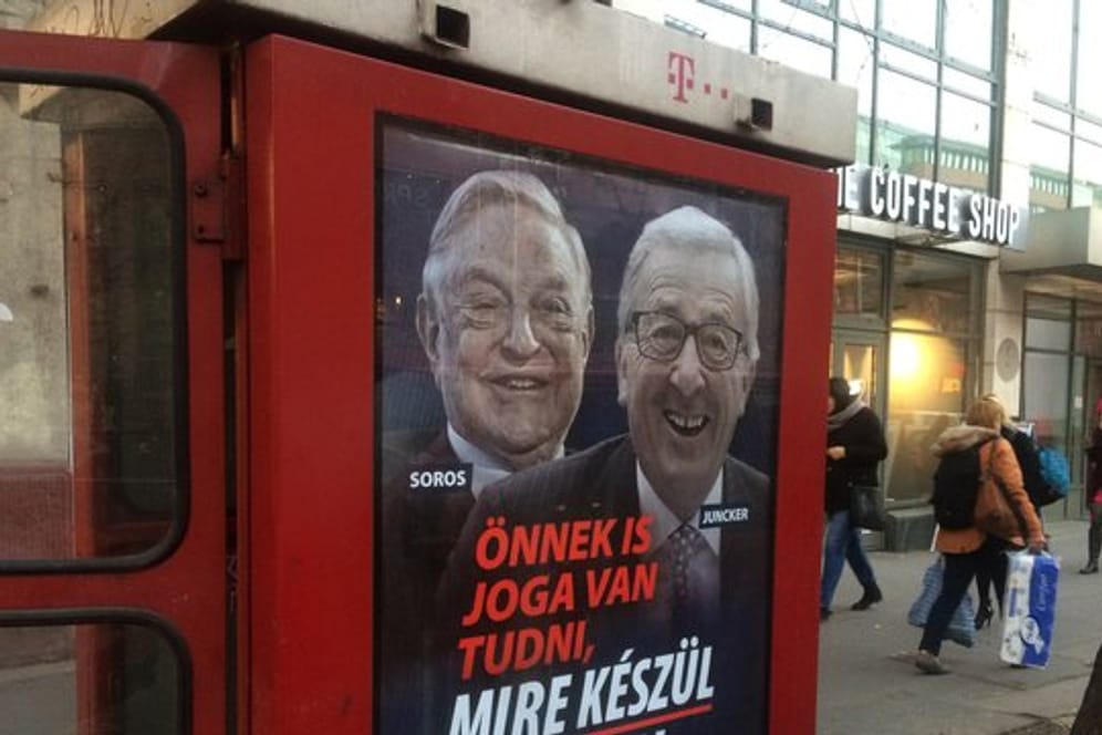 An einer Telefonzelle in Budapest hängt ein Plakat mit den Konterfeis von George Soros und Jean-Claude Juncker mit der Unterschrift "Sie haben ein Recht darauf zu wissen, was Brüssel vorhat".