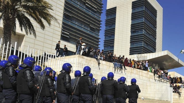 Polizisten sind in Algier aufgezogen und beobachten Demonstranten, die gegen eine erneute Kandidatur des algerischen Präsidenten Bouteflika protestieren. Polizisten sind in Algier aufgezogen und beobachten Demonstranten, die gegen eine erneute Kandidatur des algerischen Präsidenten Bouteflika protestieren.
