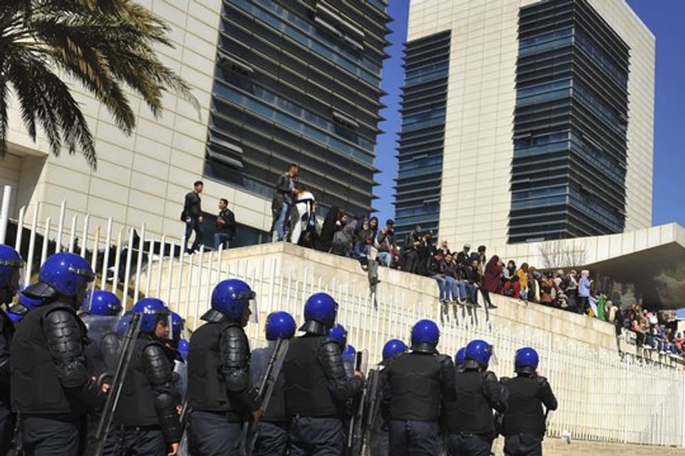 Polizisten sind in Algier aufgezogen und beobachten Demonstranten, die gegen eine erneute Kandidatur des algerischen Präsidenten Bouteflika protestieren.