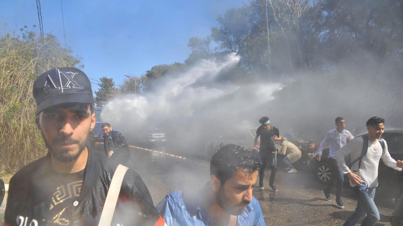 Demonstranten gehen vor einem Wasserwerfer der Polizei in Deckung: Gegen die angekündigte erneute Kandidatur des greisen und schwer kranken Amtsinhabers regt sich massiver Protest.