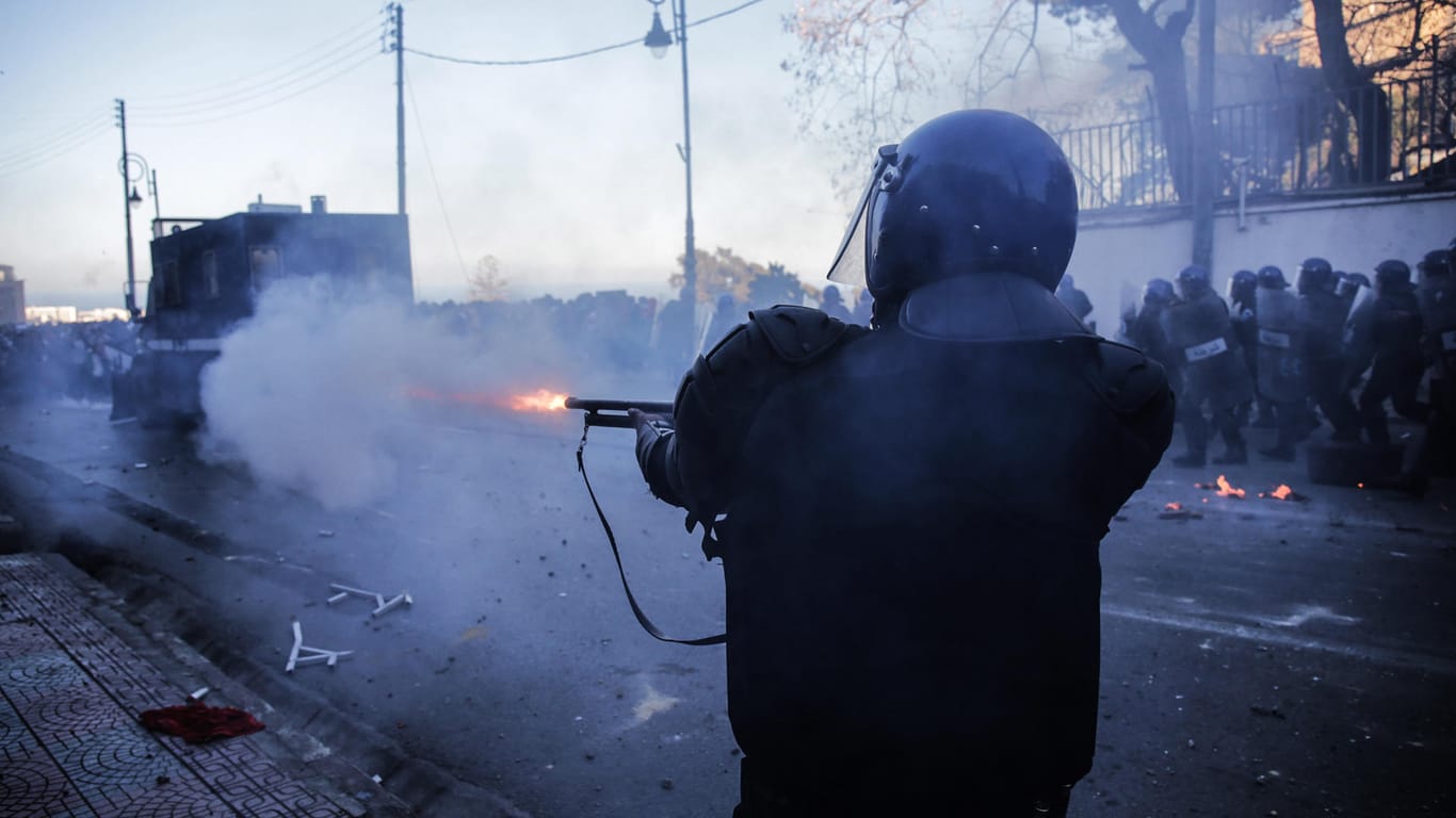 Ein Polizist feuert mit einer Waffe in Richtung von Demonstranten: Zehntausende Menschen sind in Algerien auf die Straßen gegangen, um gegen Präsident Bouteflika zu protestieren.
