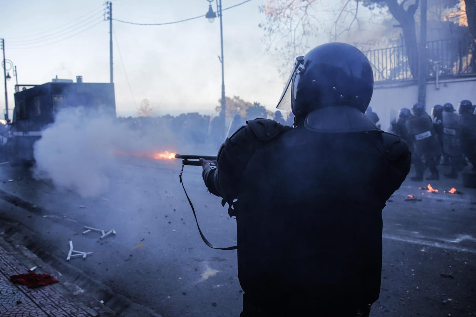 Ein Polizist feuert mit einer Waffe in Richtung von Demonstranten: Zehntausende Menschen sind in Algerien auf die Straßen gegangen, um gegen Präsident Bouteflika zu protestieren.